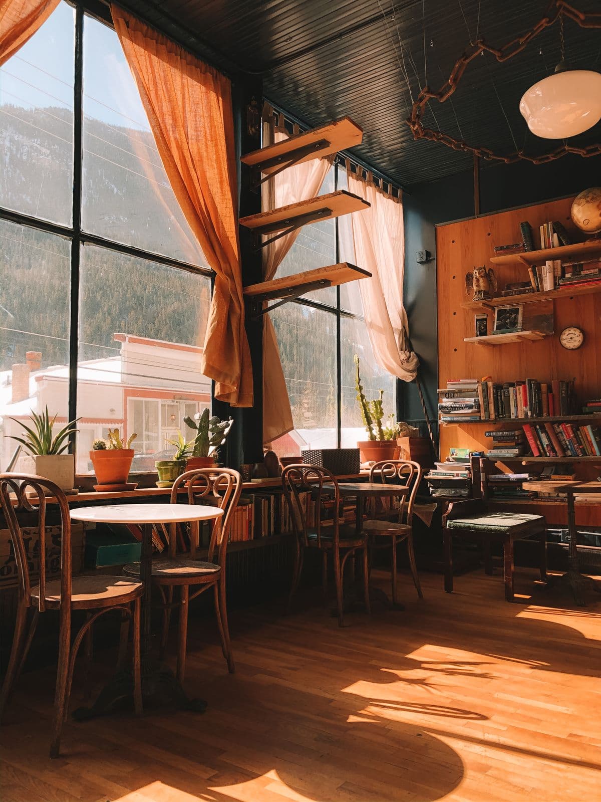 A warm, sunlit room with wooden tables, chairs and bookshelves — illustrative demo image