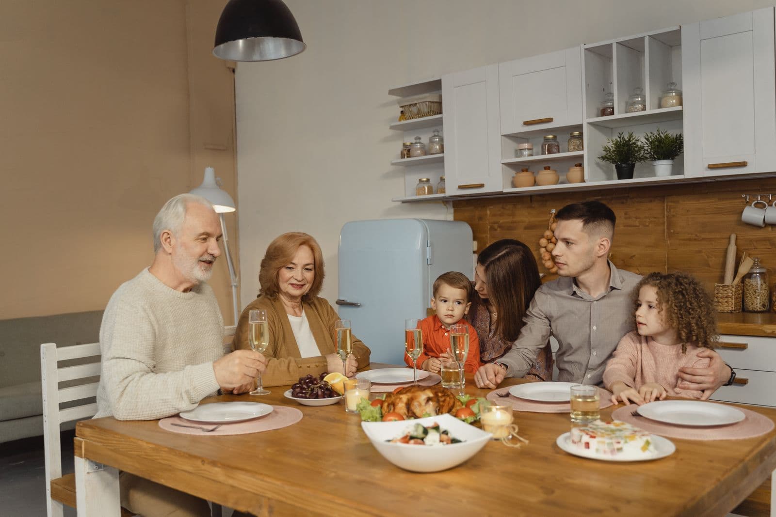 A family of several generations sharing a meal around a kitchen table — illustrative demo image