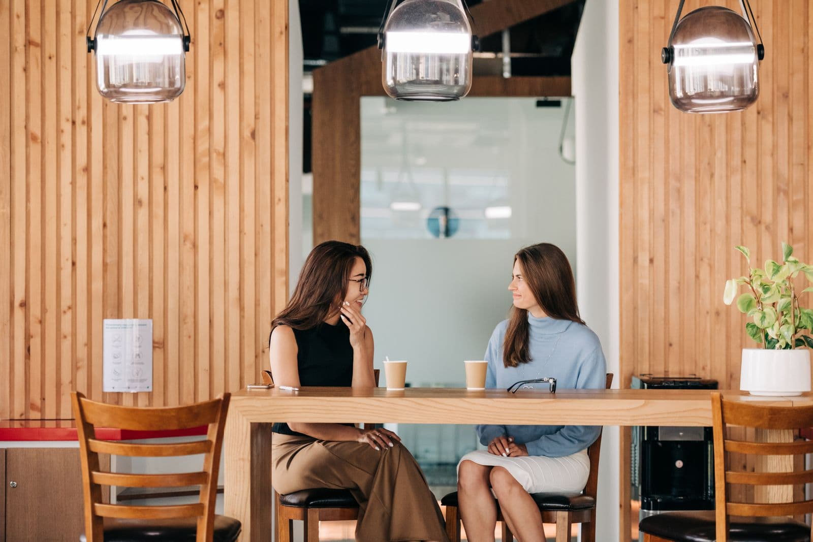 Two people talking over coffee at a table — illustrative demo image